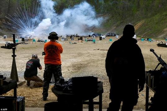People look on after an explosion goes off and a man fires a machine gun on the main firing line at the shoot on the weekend